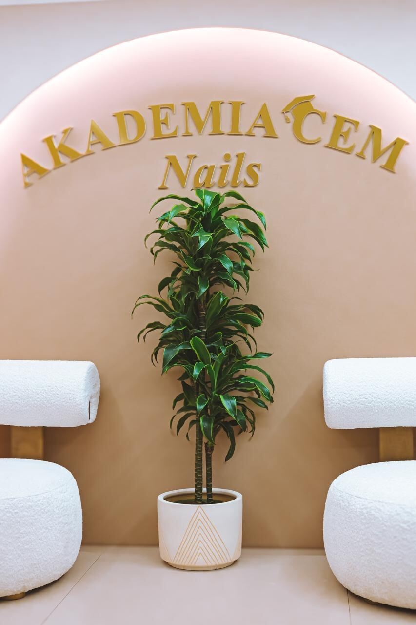 The lit arch in the Akademia CEM nail studio, with the gold Akademia CEM Nails sign above two pedicure stations.