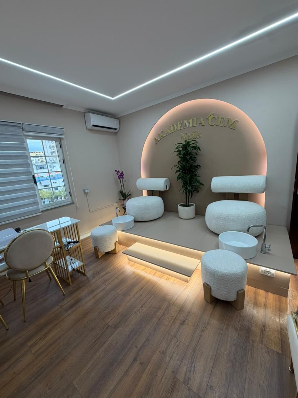 The nail studio: a pedicure platform with basins and boucle seating under the lit arch, and a manicure desk to the side.