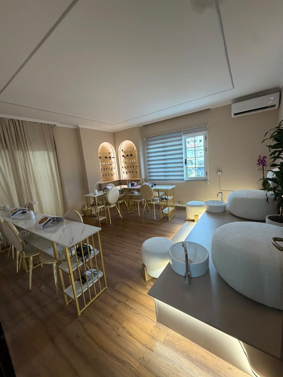 Wide view of the nail studio with two manicure desks, polish display niches and the pedicure platform.